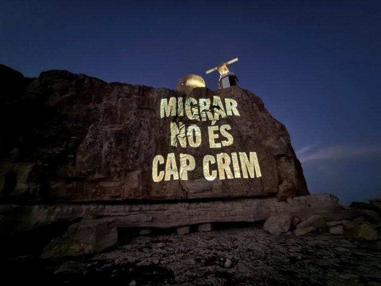 Proyección del Grupo de Acción Antifronteras Laissez Passer, en el marco de una campaña que, en verano de 2025, proyectó en la Torre de en Beu -donde se encuentra el IVE, el radar del sistema de vigilancia de embarcaciones marítimas-, da la bienvenida a las personas migrantes en 22 idiomas. | Fotografía de Laissez Passer